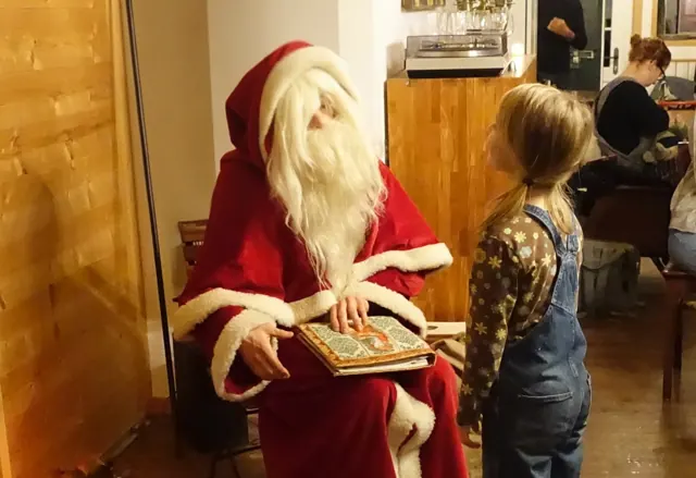 Der Samichlaus liest einem Mädchen aus seinem Buch vor