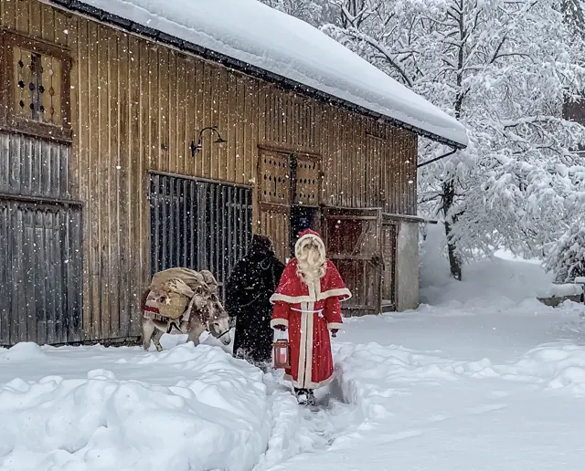 Samichlaus, Schmutzli und Esel vor einem verschneiten Stall